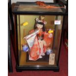 A 20th century Japanese doll, in traditional dress, housed in a glazed display case, h.38cm