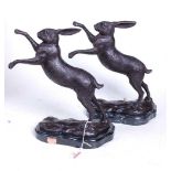 A pair of bronze models of boxing hares, each shown rearing upon a naturalistically moulded base,