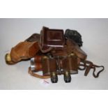 A pair of early 20th century binoculars housed in a tan leather case, together with various other