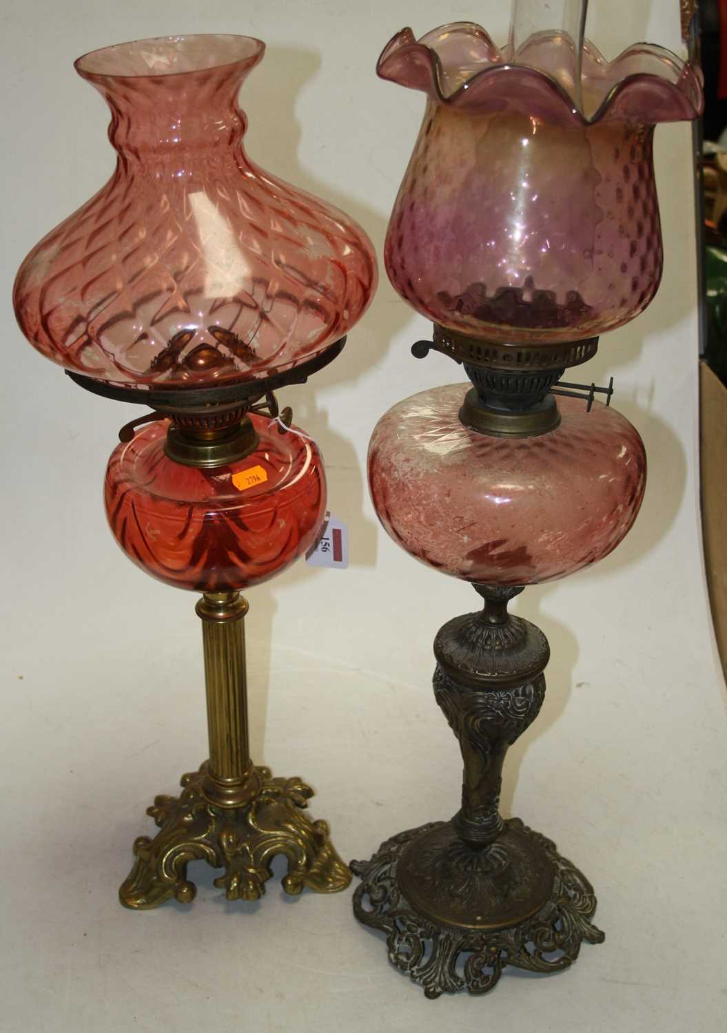 A late 19th century brass and rose-tinted glass oil lamp, h.64cm; together with another similar (2)