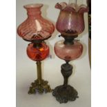 A late 19th century brass and rose-tinted glass oil lamp, h.64cm; together with another similar (2)