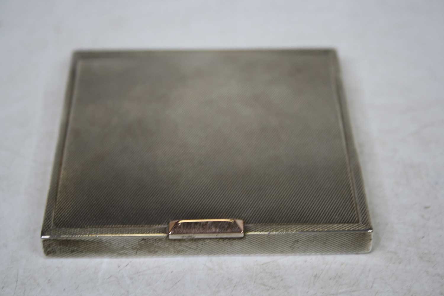 An early 20th century ladies silver powder compact of square shape having all over engine turned