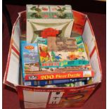 A box containing a collection of various jigsaw puzzles and games