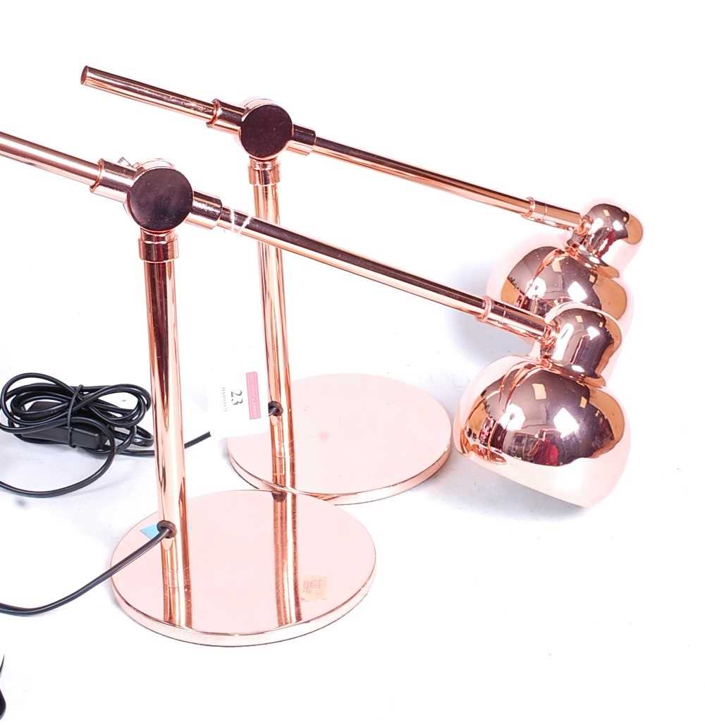 A pair of modern rose-gold coloured metal anglepoise desk lamps, each h.25cm