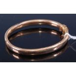 A 15ct gold hollow hinged bangle with safety chain, 11.1gCondition report: Bracelet has a couple