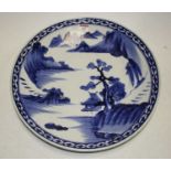 A 20th century Japanese blue and white glazed stoneware charger, decorated with a mountainous