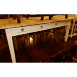 A pine farmhouse long kitchen table, having twin frieze drawers and raised on white painted square