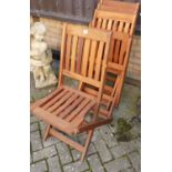 A set of four stained and slatted teak X-framed garden folding patio chairs