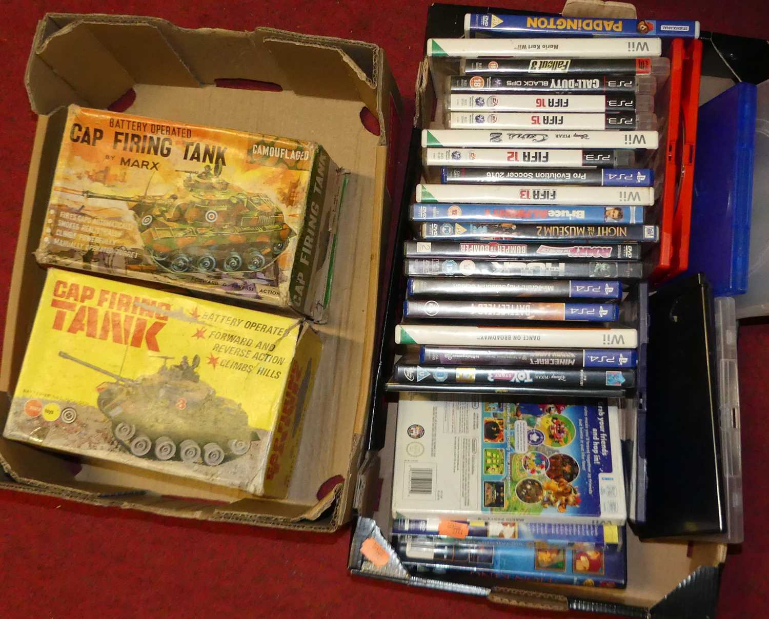 Two small boxes containing two boxed model tanks by Marx; and a collection of games and DVDs to