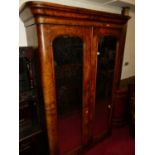 A mid-Victorian figured walnut round cornered twin mirrored door wardrobe, enclosing linen slides,