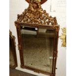 A contemporary gilt composition bevelled rectangular wall mirror, with floral scroll cresting (