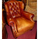 A contemporary tan leather buttoned upholstered and further brass studded wingback scroll