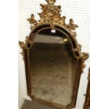 A contemporary gilt floral decorated shaped arched wall mirror, having outer marginal mirror