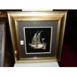 A Middle-Eastern white metal model of a small two-masted boat, the whole housed in glazed frame,