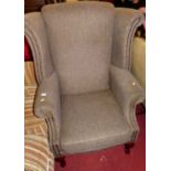 A contemporary grey fabric buttoned upholstered and further studded winged scroll armchair, raised