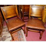 A set of five 17th century style joined oak panel backed dining chairs, having studded tan leather