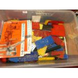 A plastic box containing used Meccano parts, mostly plates, and various Meccano magazines