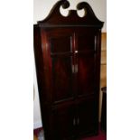 An early 19th century mahogany four door freestanding corner cupboard, having a broken arched