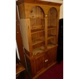 A contemporary pine bookcase cupboard, having twin arched open upper section, three adjustable