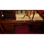 An early 20th century oak and rexine inset twin pedestal writing desk, having typical arrangement of