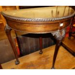 An early 20th century mahogany demi-lune baize lined fold-over card table, having rear pull-out leg,