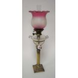 A Victorian oil lamp, having a later purple tinted frilled glass shade, above a clear glass font, on