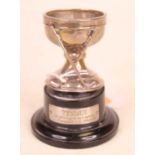 A George V silver egg-cup, surmounted by two crossed golf clubs, on ebonised stand with presentation