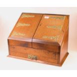 An early 20th century oak stationery cabinet, the hinged sloping front with brass strapwork type