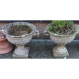 A pair of large reconstituted stone twin handled circular pedestal garden urn planters, each on