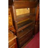 A 1930s oak four-tier stacking bookcase, having typical glazed hinged doors with single long lower