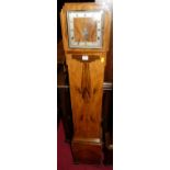 An Art Deco figured walnut grand-daughter clock, having square silver chapter ring, striking and