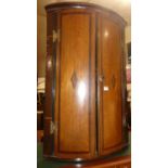 An early 19th century provincial oak and mahogany crossbanded double door bowfront hanging corner