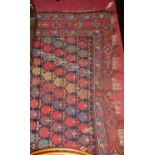 A Persian woollen red ground Bokhara rug, having a leaf decorated repeating central ground within