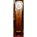 An Art Deco oak grand-daughter clock, having silvered chapter ring, twin winding holes with rod