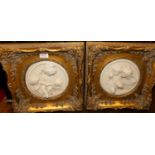 A pair of reproduction carved alabaster circular plaques, dia.17cm, in gilt composition swept
