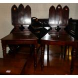 A pair of George IV mahogany panelled seat hall chairs, each with lancet arched backs in the