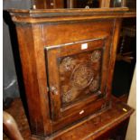 A small joined and floral relief carved oak single door hanging corner cupboard