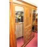 An Edwardian mahogany and satinwood strung triple wardrobe, having central cupboard door over four