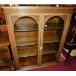 A circa 1900 relief carved oak arched double door glazed bookcase, on squat bun supports, w.