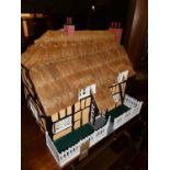 A thatched cottage two-storey dolls house, titled The Five Chimneys, with battery operated