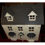 A painted three-storey dolls house, having hinged roof compartment (with damage), twin hinged