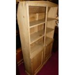 A pine freestanding three-tier open bookshelf, having twin lower cupboard doors, w.92cm