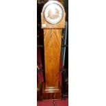 An Art Deco figured walnut grand-daughter clock, the dome top with silver chapter ring, striking and