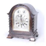 An early 20th century oak cased mantel clock, the silvered dial showing Roman numerals with slow/