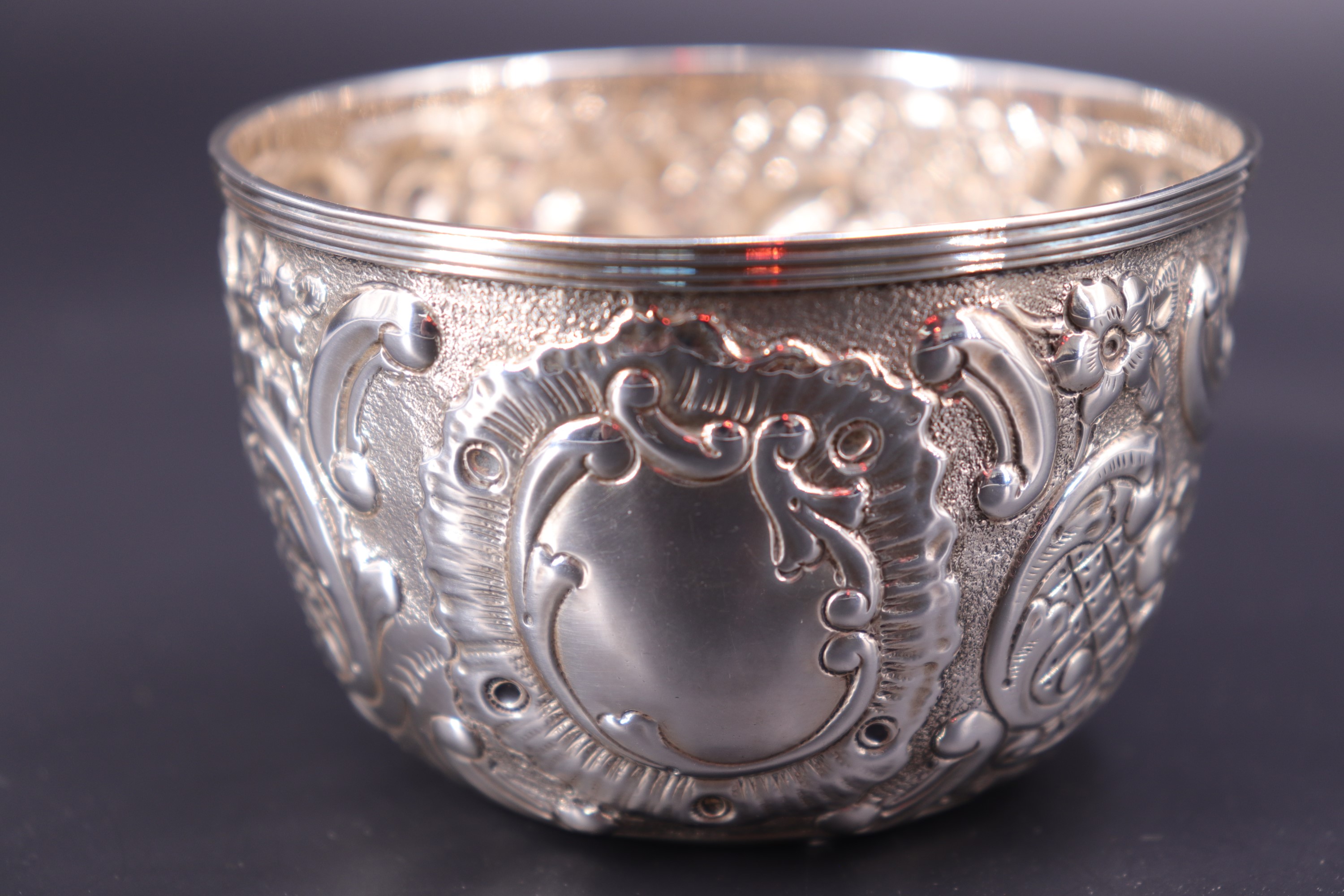 A late Victorian silver bowl, repousse-worked and engraved in a Rococo pattern centred by a vacant