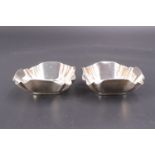 A pair of late Victorian silver salt cellars, each of cusped square section with a millegrain rim,
