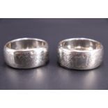 A pair of Victorian silver napkin rings, each profusely engraved and bearing a vacant shield-