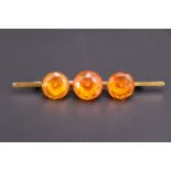 A late 19th / early 20th Century yellow metal bar brooch set with facet-cut amber, 7.5 cm, 7 g