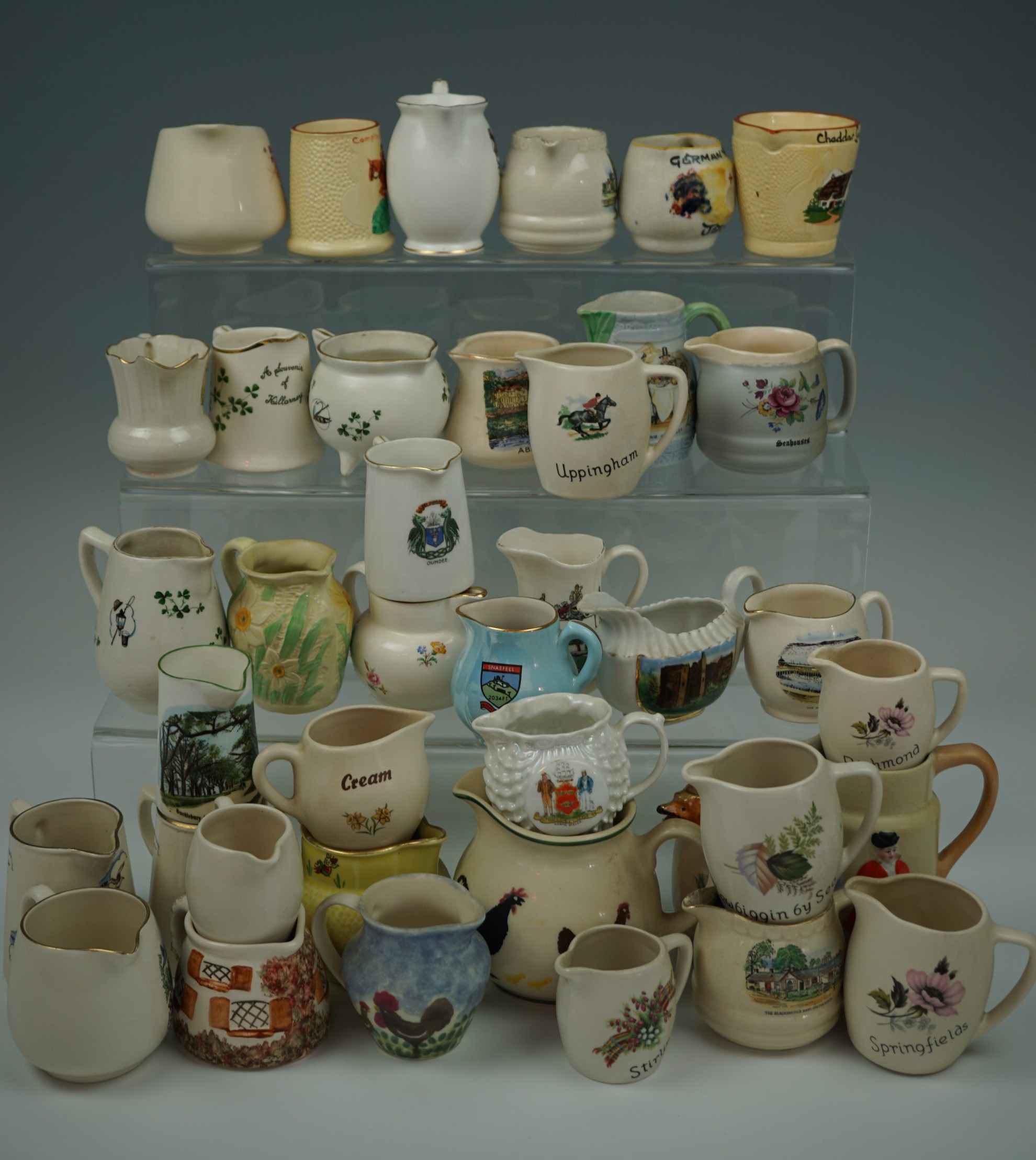 A large collection of tourist souvenir milk / cream jugs