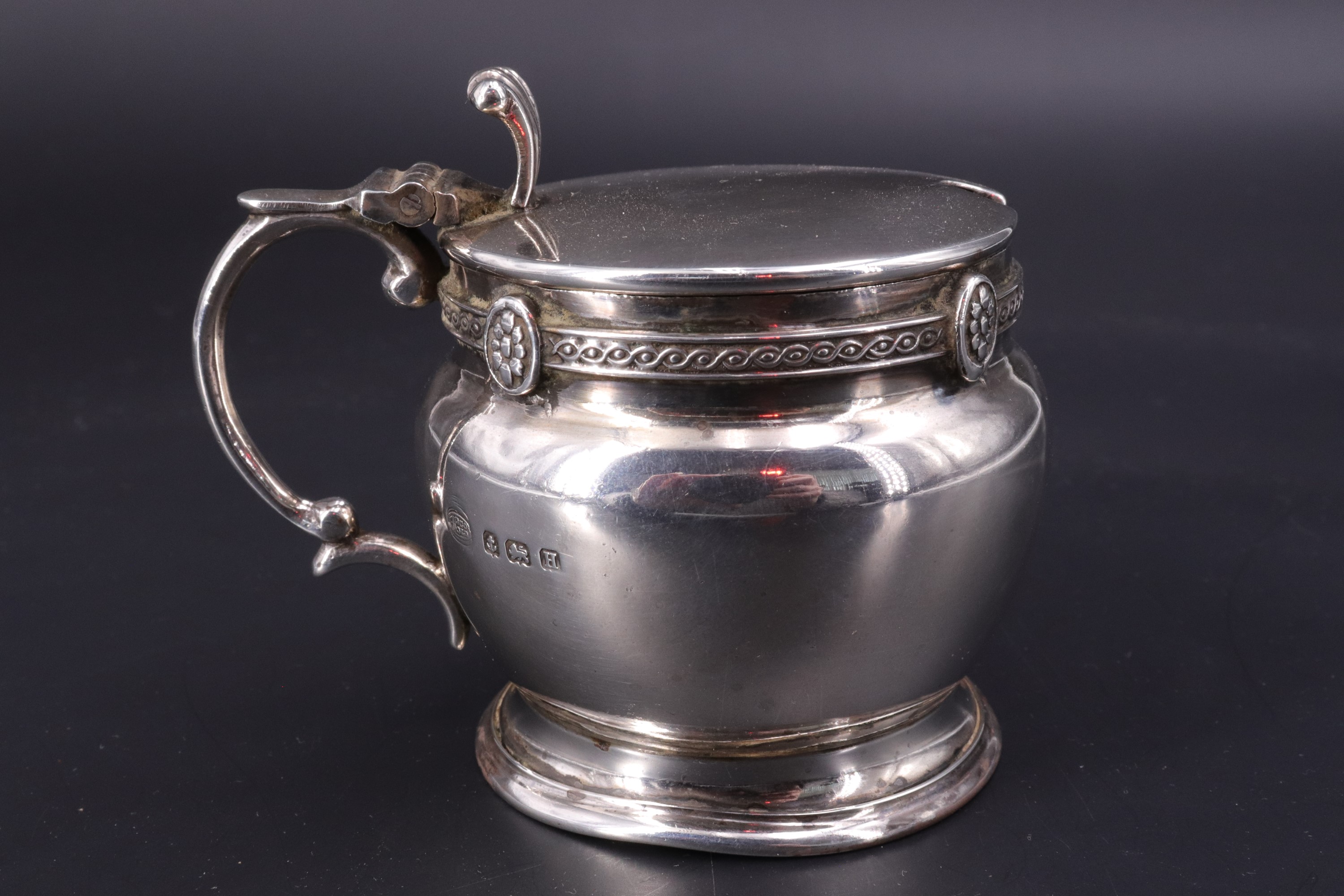 A George V silver mustard pot, of compressed ovoid form decorated with a fine guiloche-moulded